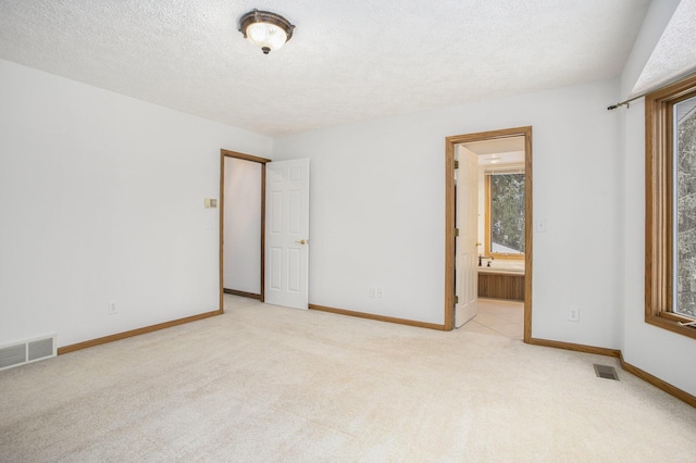 unfurnished bedroom featuring light carpet and ensuite bathroom