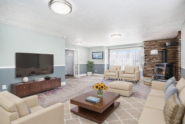 living room featuring a wood stove, a textured ceiling, and french doors