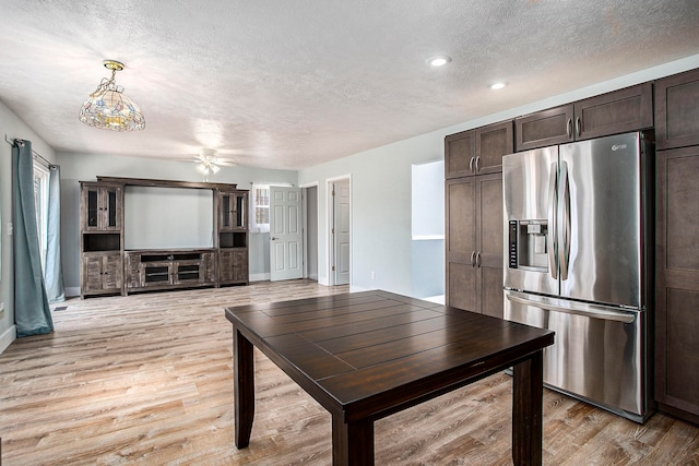 kitchen with stainless steel fridge, light hardwood / wood-style flooring, pendant lighting, and dark brown cabinets