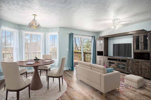 living room with ceiling fan, light hardwood / wood-style flooring, and a textured ceiling