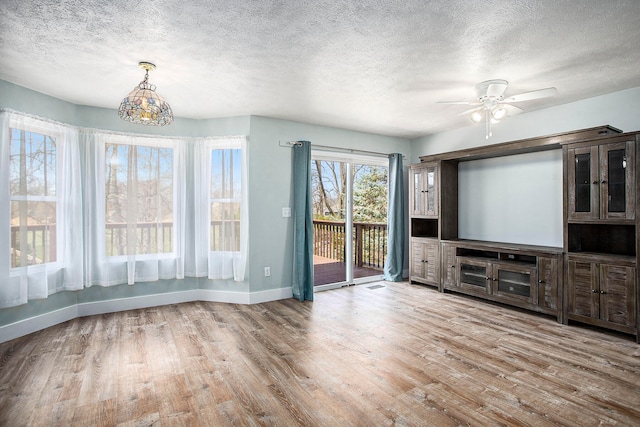 unfurnished living room with a textured ceiling, light hardwood / wood-style flooring, and ceiling fan