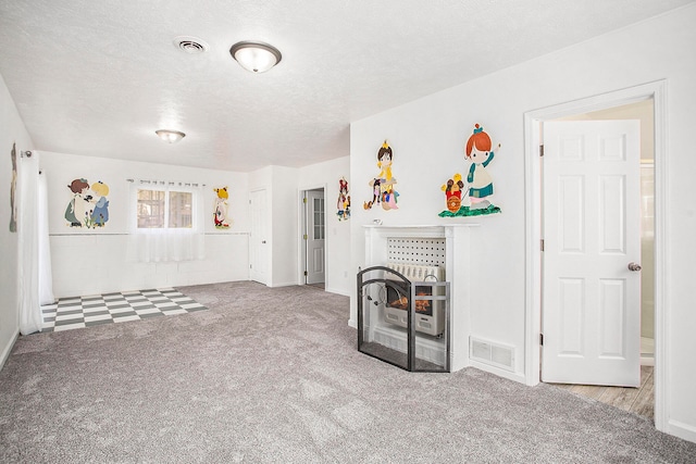 unfurnished living room with heating unit, light carpet, and a textured ceiling