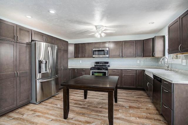 kitchen with dark brown cabinetry, sink, light hardwood / wood-style flooring, and appliances with stainless steel finishes