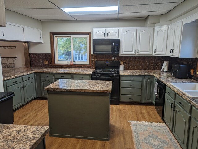 kitchen with tasteful backsplash, a paneled ceiling, white cabinets, and black appliances