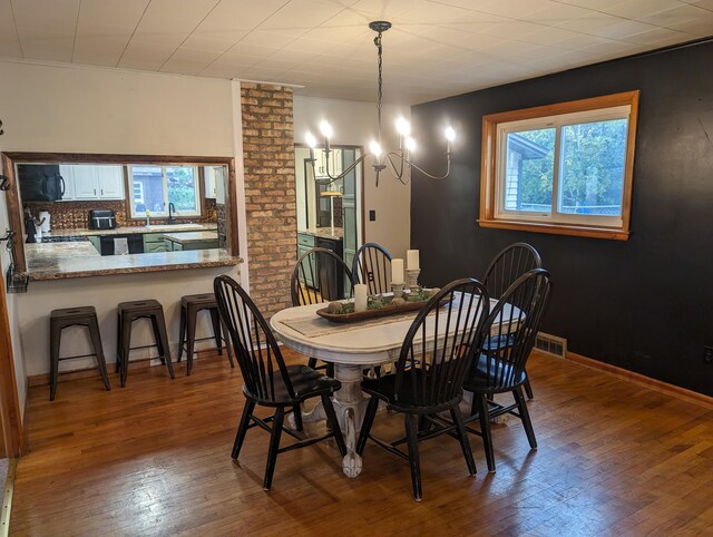 dining area with hardwood / wood-style floors, a notable chandelier, and sink