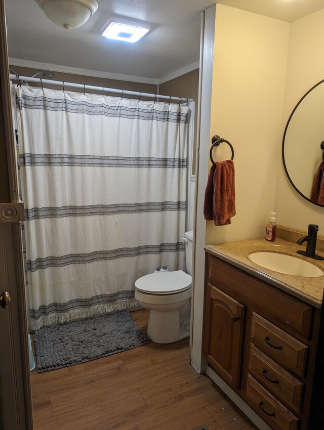 bathroom featuring toilet, vanity, wood-type flooring, and ornamental molding