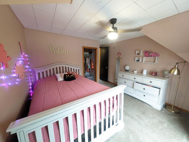 bedroom with a walk in closet, vaulted ceiling, ceiling fan, light colored carpet, and a closet