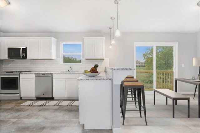 kitchen featuring sink, hanging light fixtures, plenty of natural light, white cabinetry, and stainless steel appliances