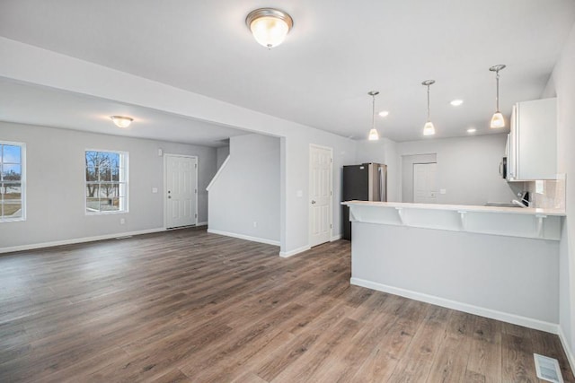 kitchen featuring pendant lighting, white cabinetry, dark hardwood / wood-style flooring, kitchen peninsula, and stainless steel appliances