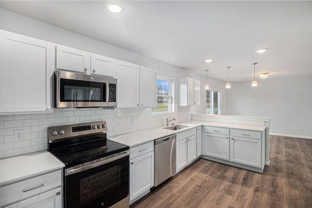 kitchen featuring kitchen peninsula, appliances with stainless steel finishes, sink, decorative light fixtures, and white cabinetry