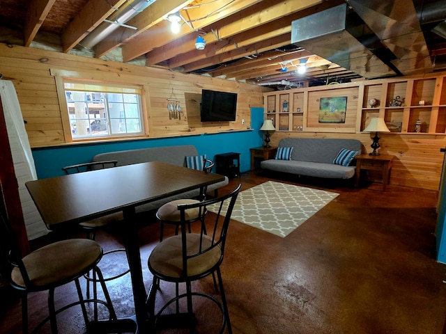 dining area featuring beamed ceiling and wood walls