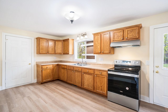 kitchen with a wealth of natural light, stainless steel electric range oven, sink, and light hardwood / wood-style floors