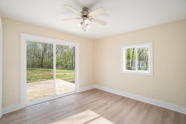 empty room featuring plenty of natural light, ceiling fan, and light hardwood / wood-style flooring