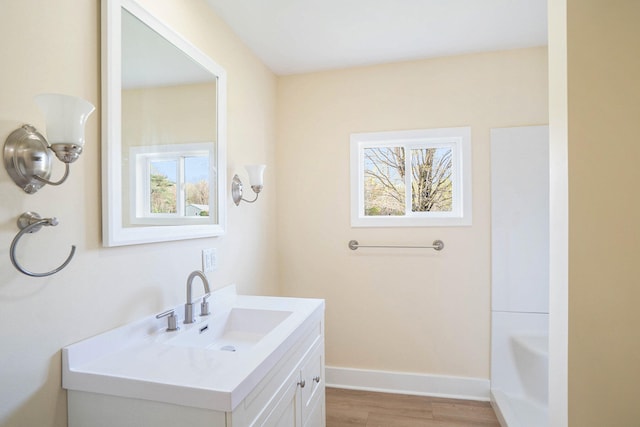 bathroom with a washtub, wood-type flooring, vanity, and plenty of natural light