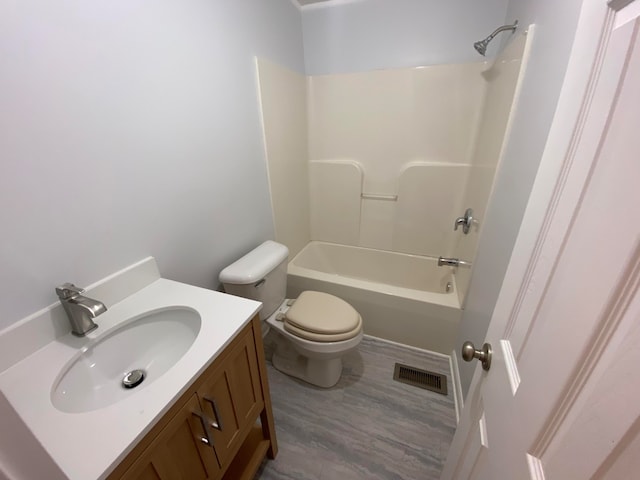 full bathroom with vanity, washtub / shower combination, wood-type flooring, and toilet