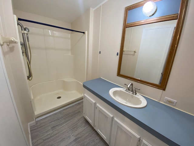 bathroom with hardwood / wood-style flooring, vanity, and walk in shower