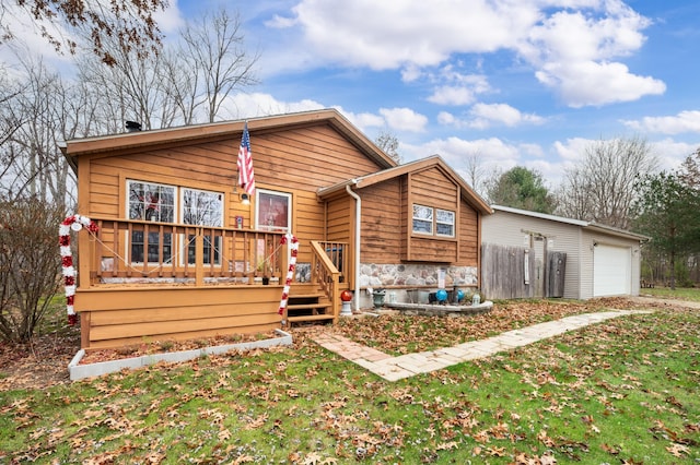 rear view of house featuring a garage, a yard, and a wooden deck