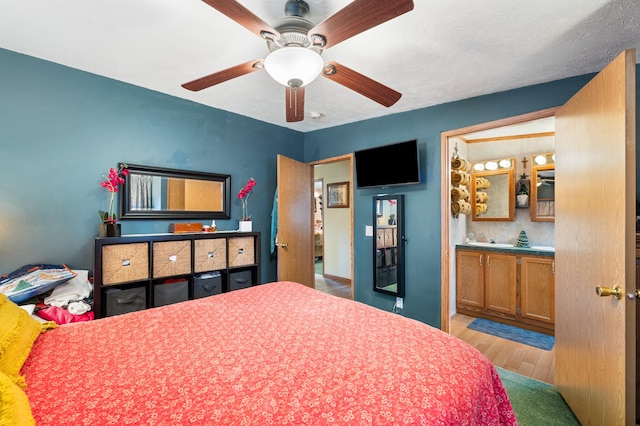 bedroom featuring ceiling fan, ensuite bath, and light hardwood / wood-style flooring