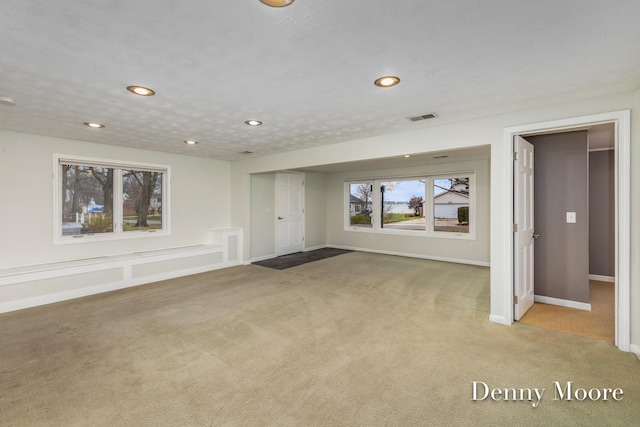 unfurnished living room featuring light carpet and a textured ceiling