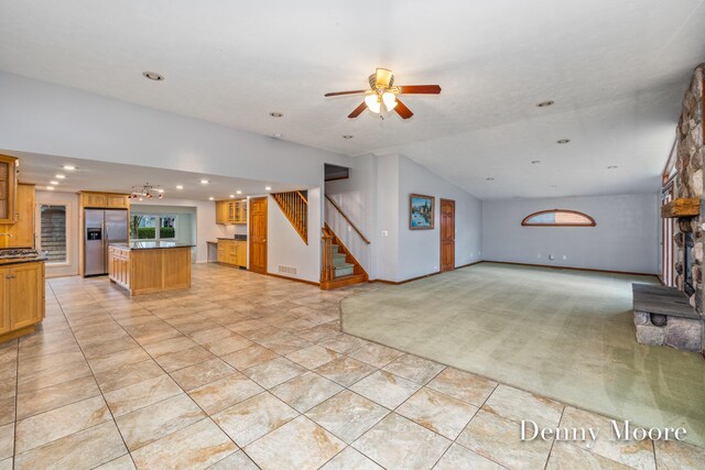 unfurnished living room featuring ceiling fan, light colored carpet, and vaulted ceiling