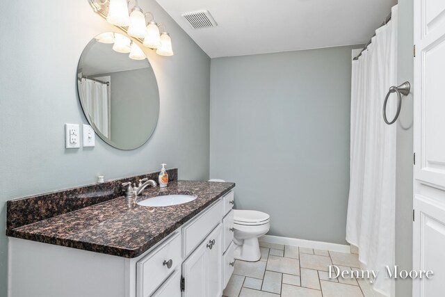 bathroom with toilet, vanity, and tile patterned floors