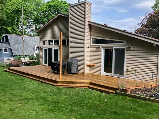 rear view of house with a lawn and a wooden deck