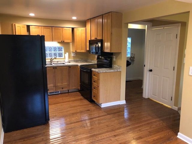 kitchen featuring hardwood / wood-style floors, sink, light brown cabinetry, and black appliances