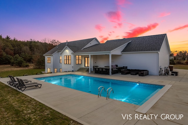 pool at dusk with outdoor lounge area and a patio area