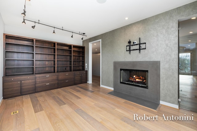 unfurnished living room featuring light hardwood / wood-style floors and track lighting