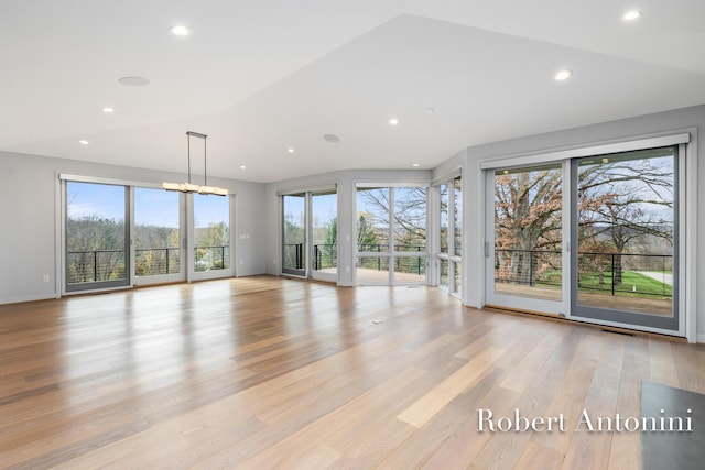 unfurnished living room featuring lofted ceiling, a healthy amount of sunlight, and light hardwood / wood-style floors