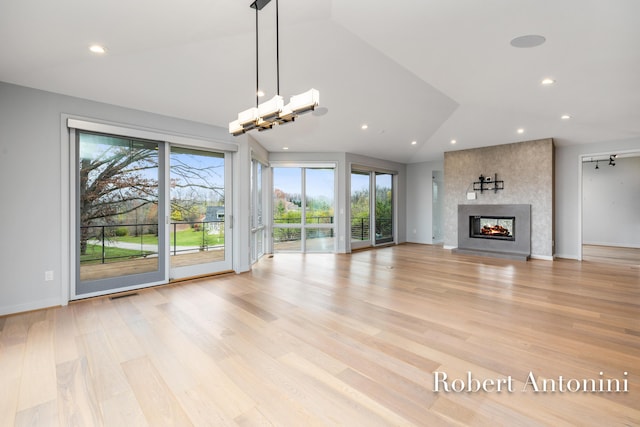 unfurnished living room featuring a multi sided fireplace, light wood-type flooring, and lofted ceiling