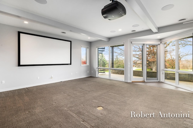 carpeted cinema room featuring beam ceiling