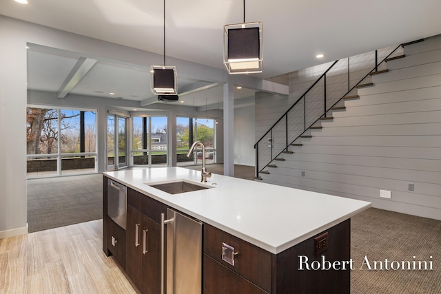 kitchen with dark brown cabinetry, a kitchen island with sink, a healthy amount of sunlight, and sink