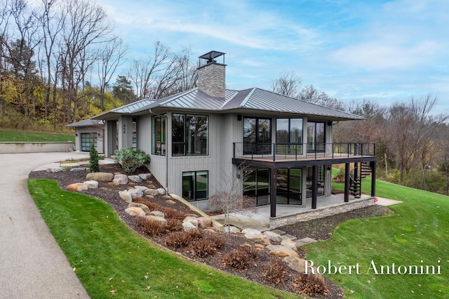 view of home's exterior with a deck, a patio area, and a lawn