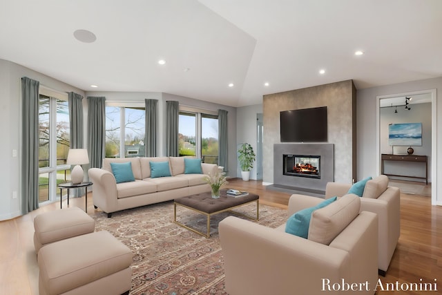 living room featuring a large fireplace, lofted ceiling, and light hardwood / wood-style flooring