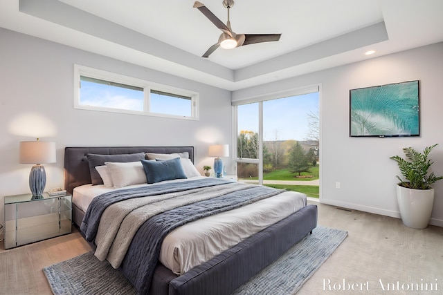 bedroom with a tray ceiling, multiple windows, and ceiling fan