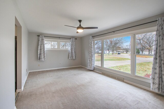 carpeted empty room with a wealth of natural light and ceiling fan