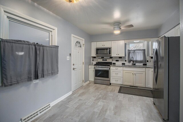 kitchen with white cabinetry, sink, light hardwood / wood-style floors, and appliances with stainless steel finishes