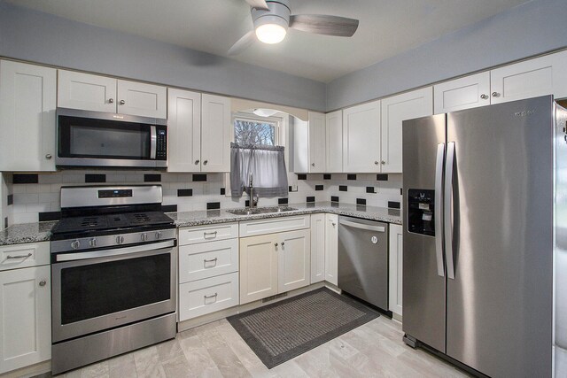 kitchen featuring white cabinets, appliances with stainless steel finishes, decorative backsplash, and sink