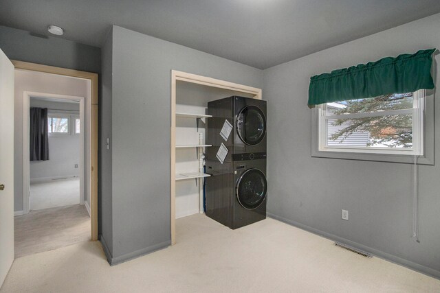 laundry area featuring light carpet and stacked washer and dryer