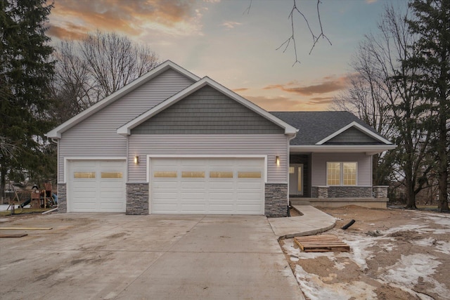 view of front of house featuring a garage, stone siding, and driveway