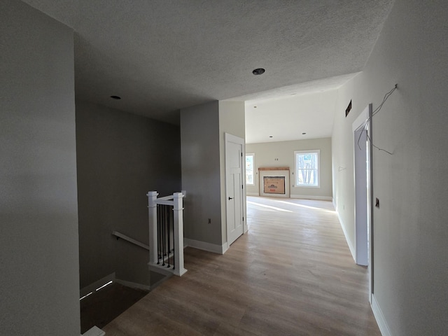 hall with wood-type flooring and a textured ceiling