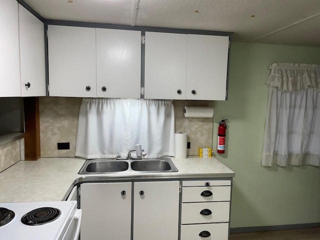 kitchen with white cabinets, white stove, and sink