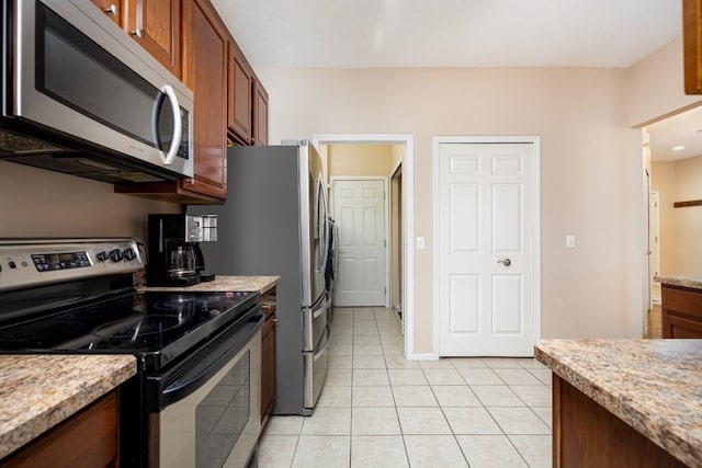 kitchen featuring light tile patterned flooring, light stone countertops, and appliances with stainless steel finishes