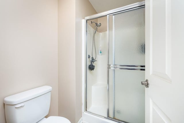 bathroom featuring a shower with shower door and toilet