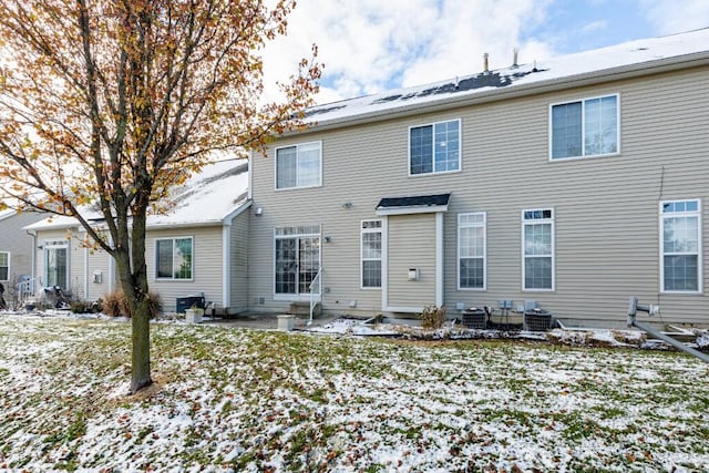 snow covered house with cooling unit and a patio