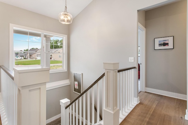 stairs with an inviting chandelier, hardwood / wood-style floors, and vaulted ceiling