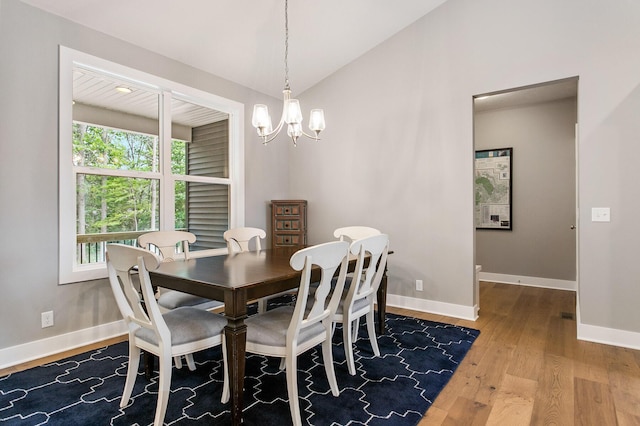 dining area featuring hardwood / wood-style flooring, vaulted ceiling, and a notable chandelier