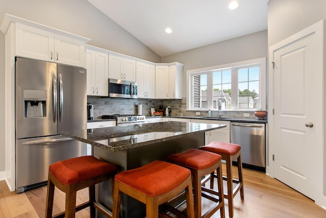 kitchen with a kitchen island, a breakfast bar, sink, white cabinets, and stainless steel appliances