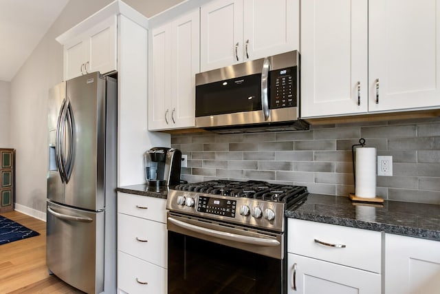 kitchen featuring dark stone countertops, appliances with stainless steel finishes, light hardwood / wood-style floors, decorative backsplash, and white cabinets